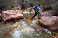 26-Kenny_hopping_across_pretty_colorful_rocks_with_flowing_water