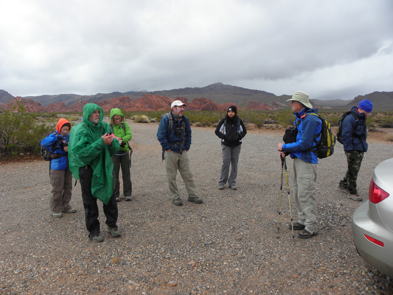 03-cold_wet_group_at_beginning_of_hike_receiving_orientation_from_Ed-wow_Harlan_with_pants_and_poncho